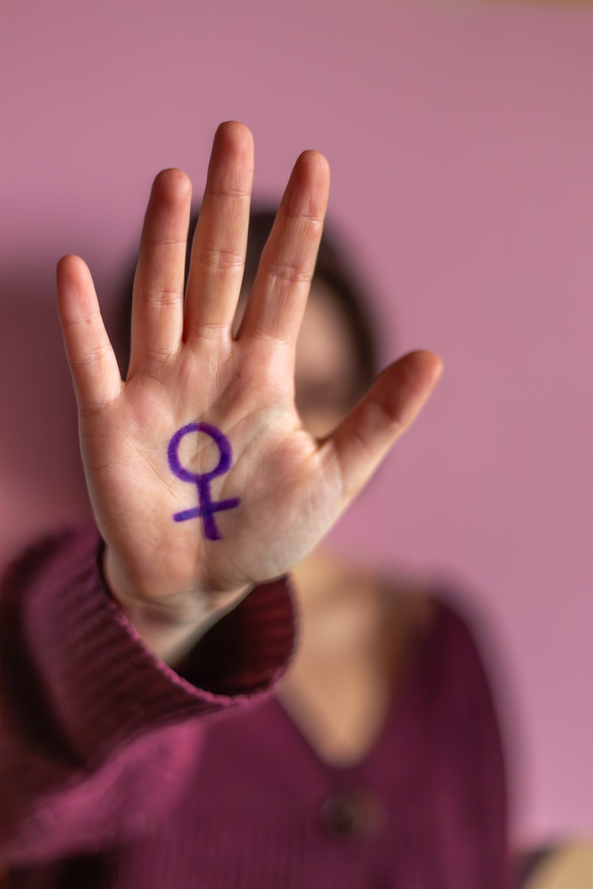 Mulher com s&iacute;mbolo feminista na m&atilde;o representando luta contra viol&ecirc;ncia